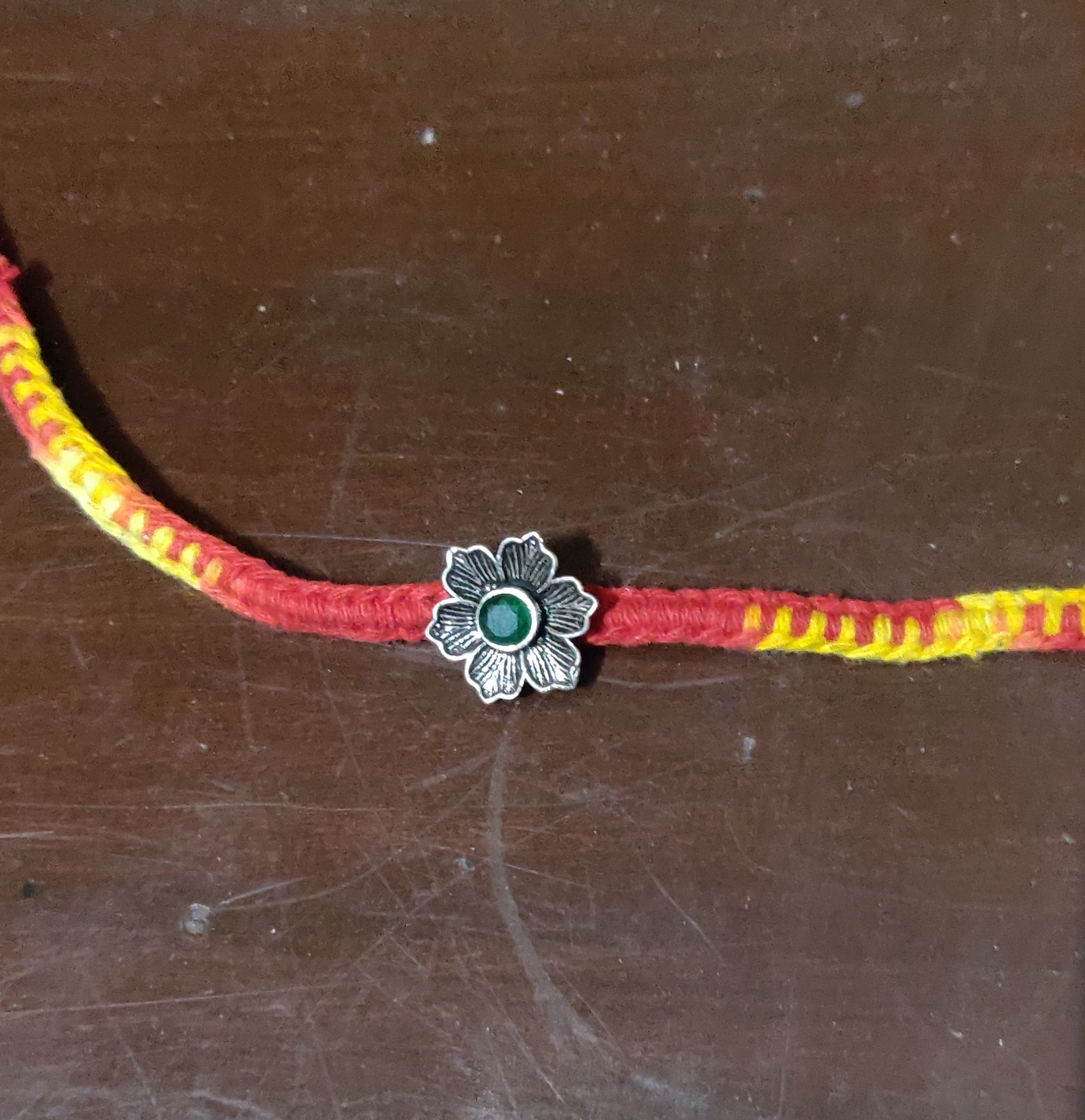 Silver flower with green stone rakhi